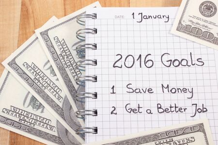 New years resolutions save money and get better job written in notebook and currencies dollar