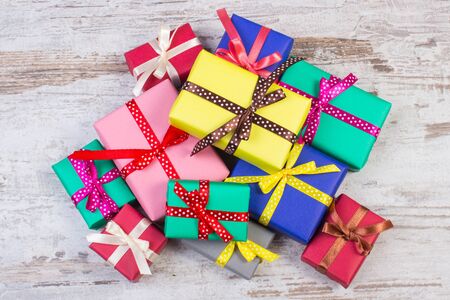 Heap of wrapped colorful gifts for Christmas, birthday or other celebration on old wooden white plankの写真素材