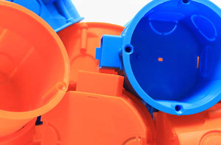 Heap of blue and orange plastic electrical boxes, components for electrical installations, accessories for engineering jobsの写真素材