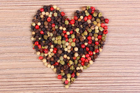 Heart shaped fresh colored pepper on wooden table, seasoning for cooking, healthy nutrition, symbol of loveの写真素材