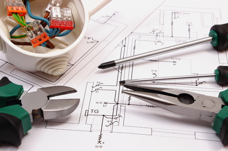 Metal pliers, screwdriver and cable connections in electrical box lying on electrical construction...