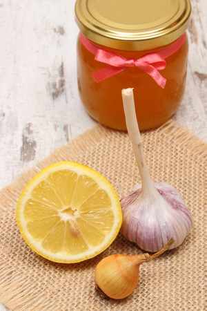 Fresh organic onion, garlic, lemon and honey in glass jar on old wooden background, healthy nutrition, strengthening immunity and treatment of fluの写真素材
