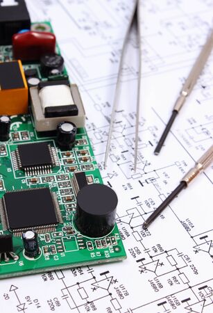 Printed circuit board with electrical components and precision tools lying on construction drawing of electronics, drawings and precision tools for engineer jobs, technologyの写真素材