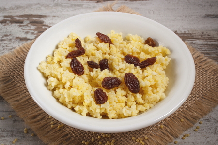 Fresh cooked millet groats with raisins on white plate, concept of healthy food, nutrition and nutritious breakfastの写真素材