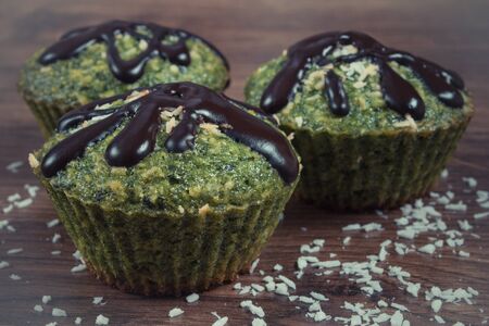 Vintage photo, Homemade fresh muffins baked with wholemeal flour with spinach, desiccated coconut and chocolate glaze, delicious, healthy dessert or snackの写真素材