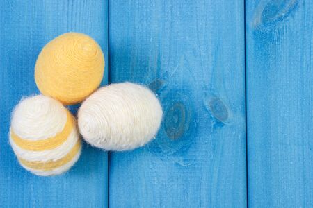 Easter eggs wrapped woolen string on blue wooden boards, copy space for inscription or text, decoration for Easterの写真素材