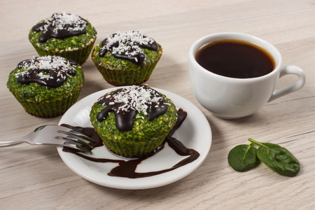 Homemade muffins baked with wholemeal flour with spinach, desiccated coconut and chocolate glaze, cup of coffee, delicious, healthy dessert or snackの写真素材