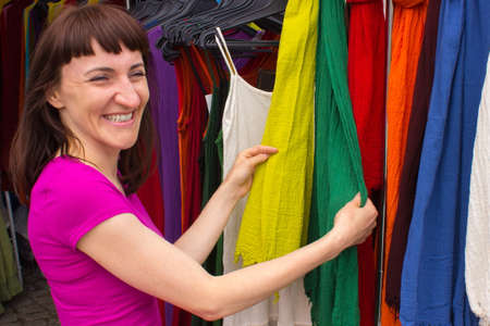 Woman looking at clothing hanging on hangers, shopping clothes on stall at the bazaarの写真素材