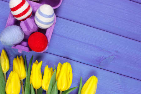 Bouquet of fresh yellow tulips and Easter eggs wrapped woolen string on wooden boards, copy space...