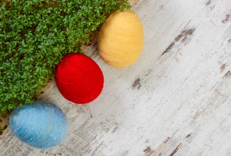 Easter eggs wrapped woolen string and green cuckooflower cress on old wooden background, copy space for inscription or text, decoration for Easterの写真素材