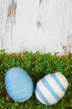 Easter eggs wrapped woolen string and green cuckooflower cress on old wooden background, copy space for inscription or text, decoration for Easterの写真素材