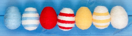 Colorful Easter eggs wrapped woolen string on blue wooden boards, decoration for Easterの写真素材