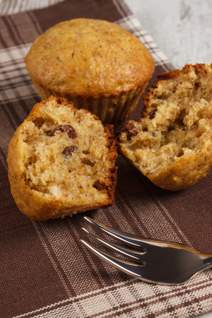 Fresh muffins with oatmeal baked with wholemeal flour and fork on checkered tablecloth, concept of delicious, healthy dessert or snackの写真素材