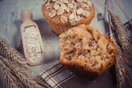 Vintage photo, Fresh muffins with oatmeal baked with wholemeal flour, rye flour and ears of rye grain, concept of delicious, healthy dessert or snackの写真素材