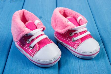 Pair of pink baby shoes on blue boards, concept of extending family and expecting for babyの写真素材
