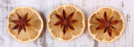 Slices of fresh dried lemon and star anise lying on old rustic wooden backgroundの写真素材