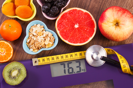 Digital electronic bathroom scale for weight of human body, tape measure and stethoscope with fresh and dried fruits, healthcare, healthy lifestyles and slimming conceptの写真素材