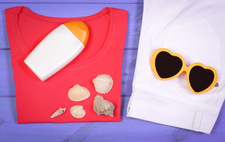 Clothing for woman and accessories for vacation and summer on purple boards, sunglasses, sun lotion,...