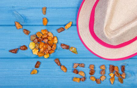 Shape of sun with word sun made of amber stones and straw hat for vacation and summer on blue boardsの写真素材