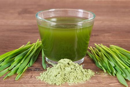 Heap of young powder barley, barley grass and beverage on wooden backgroundの写真素材
