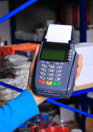 Hand of woman using payment terminal in an electrical shopの写真素材