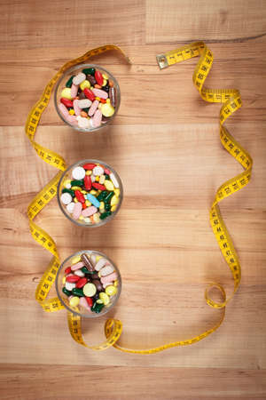 Tape measure and colorful medical pills, capsules or supplements for therapy or weight loss, concept of treatmentの写真素材
