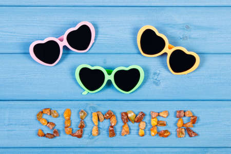 Inscription summer made of amber stones and sunglasses on blue boardsの写真素材