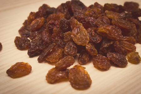 Vintage photo, Heap of brown raisins lying on wooden tableの写真素材