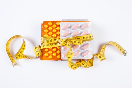 Blisters of medical pills, tablets, capsules or supplements wrapped tape measureの写真素材