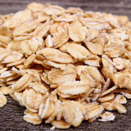 Heap of organic oatmeal, oat flakes on wooden background, concept for healthy eating and nutrition