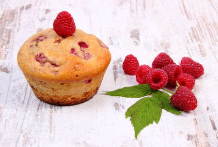 Homemade baked cupcake with raspberries and fresh fruits on plate on old rustic wooden background, delicious dessertの写真素材
