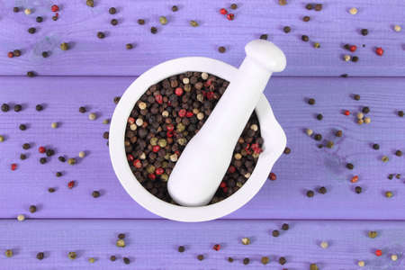 Colorful pepper in white glass mortar on purple boards, seasoning for cooking