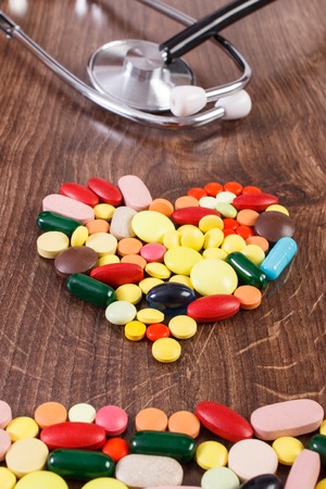 Heart shaped colorful medical pills, capsules or supplements for therapy and stethoscope, concept of treatment and health careの写真素材