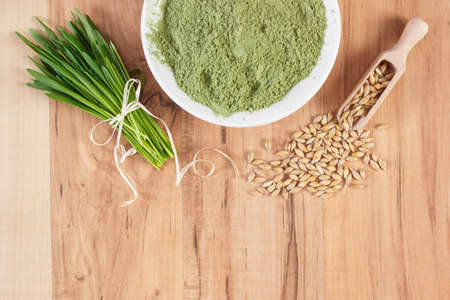 Young powder barley in bowl, barley grass and grain on wooden background, healthy nutrition and lifestyle, body detox, copy space for textの写真素材