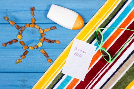Amber stones in shape of sun, accessories for vacation, inscription summer 2016 on sheet of paper