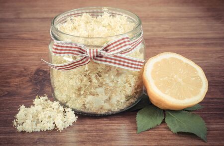 Vintage photo, Glass of elderberry flowers and lemon for preparing healthy juice on rustic board, alternative medicine and therapyの写真素材