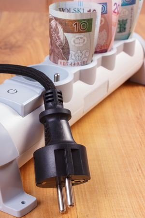Rolls of polish currency money in electrical extension and disconnected plug, power board, concept...