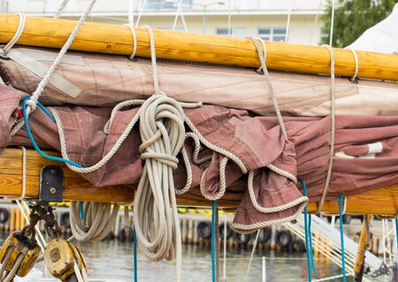 Yachting, parts of old wooden sailboat in port of sailing, coiled rope, sail, details of yacht