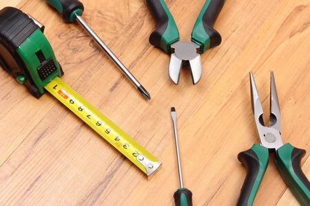 Metal pliers, electrical screwdrivers and tape measure on wooden plank, work tools and accessories for engineering jobsの写真素材