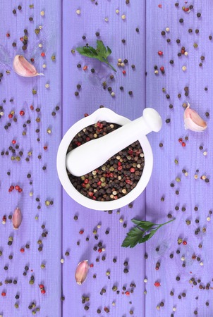 Colorful pepper in white glass mortar on purple boards, seasoning for cookingの写真素材