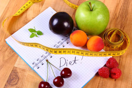 Fresh fruits and tape measure with notebook for writing notes, concept of slimming, diet and healthy nutritionの写真素材