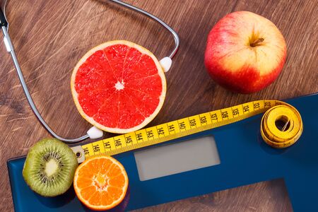 Digital electronic bathroom scale for weight of human body, tape measure and medical stethoscope with fresh fruits, concept of healthcare, healthy lifestyles and slimmingの写真素材