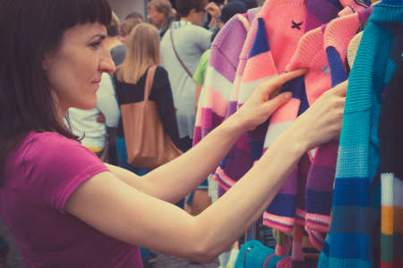 Vintage photo, Woman looking at clothing hanging on hangers, shopping clothes on stall at the bazaarの写真素材