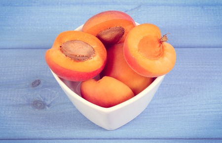 Vintage photo, Fresh natural ripe apricots in glass white bowl on boards, concept of healthy dessert and nutritionの写真素材