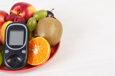Glucose meter for measuring and checking sugar level and fresh fruits, diabetes and healthy nutrition, copy space for textの写真素材