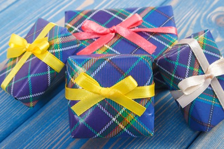 Wrapped colorful gifts with ribbons for Christmas, Valentine, birthday or other celebration lying on old boardsの写真素材