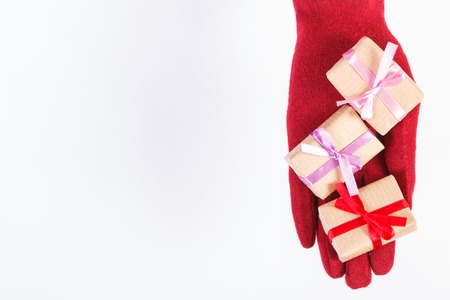 Hand of woman in red woolen gloves and wrapped gifts for Christmas, Valentine, birthday or other...