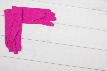 Pink gloves for woman on white boards, warm clothing for autumn or winter, copy space for textの写真素材