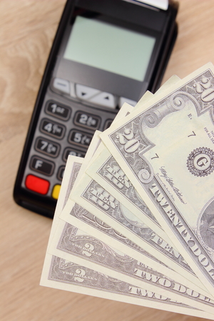 Currencies dollar and credit card reader on wooden desk, payment terminal, finance and banking conceptの写真素材