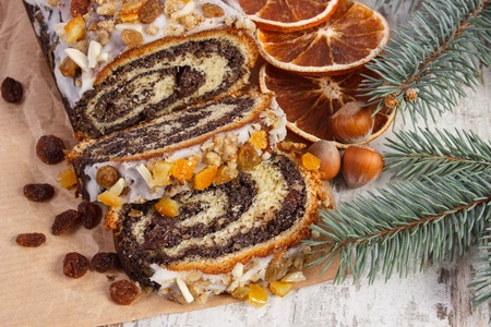 Homemade poppy seeds cake and spruce branches on rustic board, dessert and decoration for Christmas, rolled up traditional polish poppy pieの写真素材